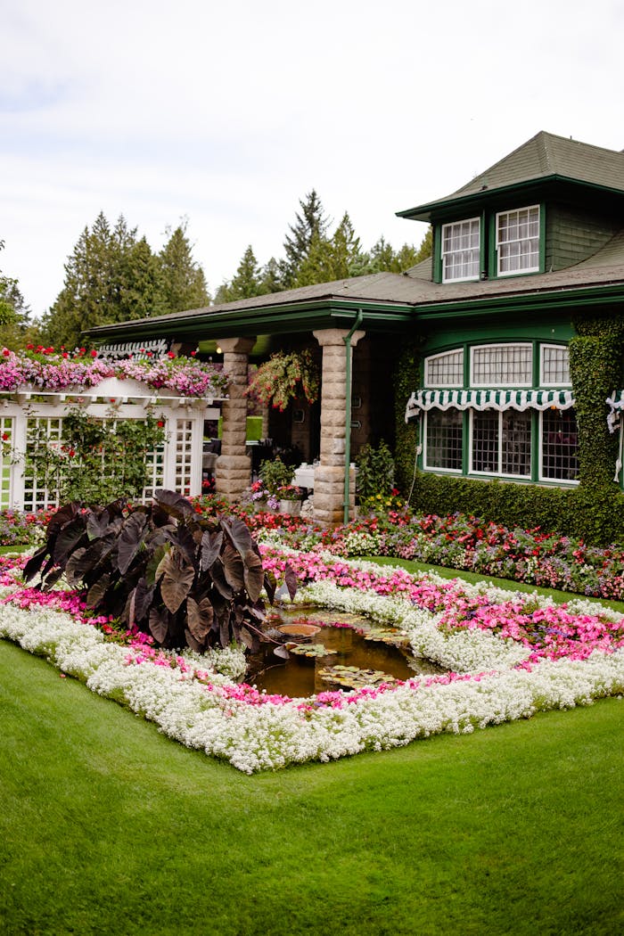 A beautifully landscaped garden with vibrant flowers in front of a classic green house, showcasing timeless elegance.